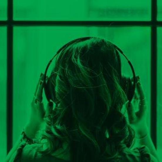 Billede med grønt filter af et kvinde der holder på sine hovedtelefoner set fra ryggen.