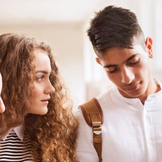 Fem unge der står samlet og kigger ned på noget.