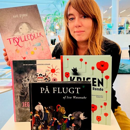 Kvindelig børnebogsformidler siddende med fire udvalgte bøger