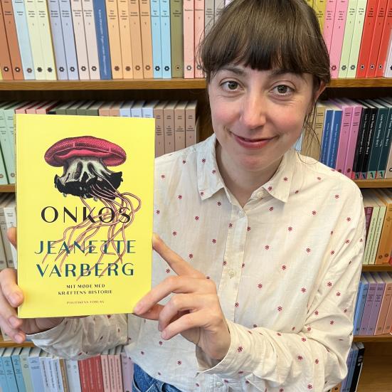 Bibliotekar stående med "Onkos" foran en bogreol.