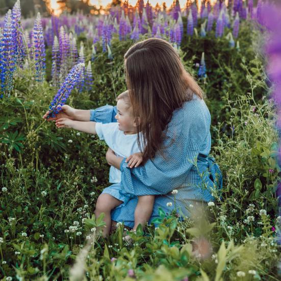 Mor og barn siddende i en blomstermark.