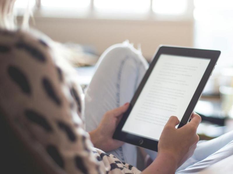 Person, der sidder i en sofa, med en ebogslæser.