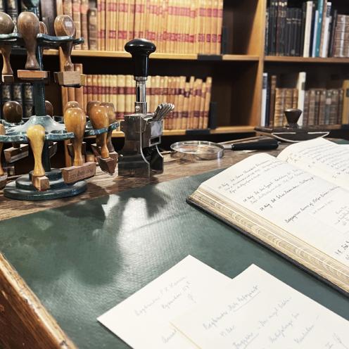 Billedet viser en gammel skrivepult med stempler og gamle papirer på