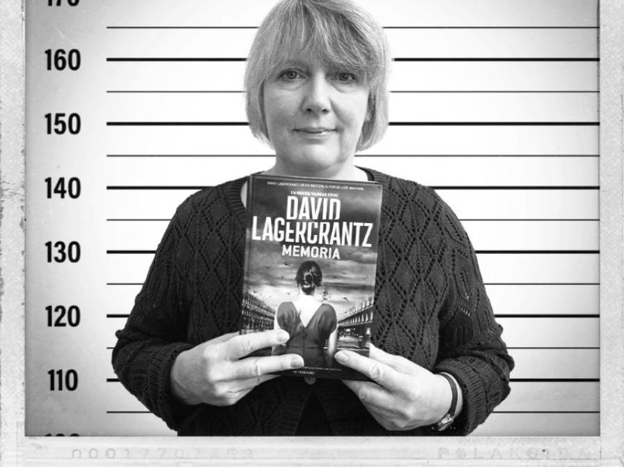 Et sort/hvid billede af medarbejder, der holder en bog og er i en mugshot-æstetik