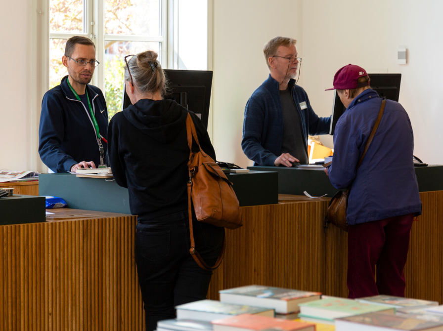 To borgere bliver betjent i bibliotekets infocenter