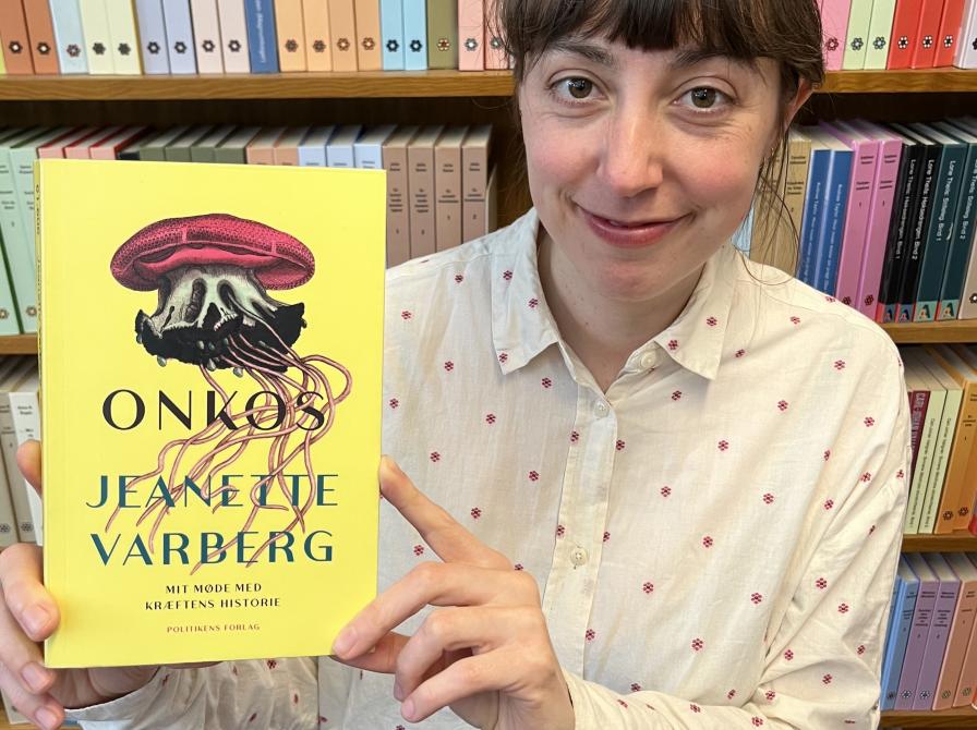 Bibliotekar stående med "Onkos" foran en bogreol.
