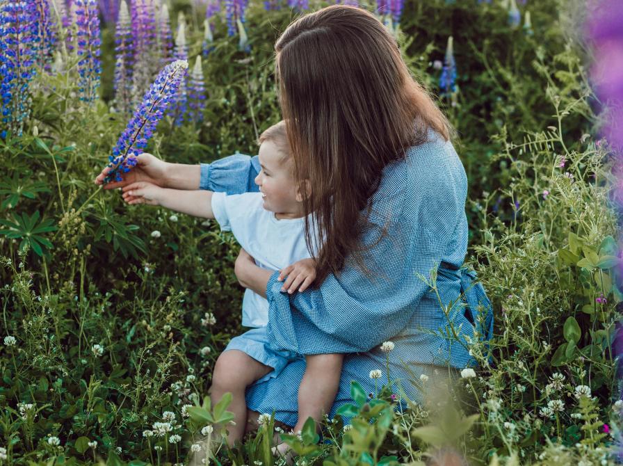 Mor og barn siddende i en blomstermark.